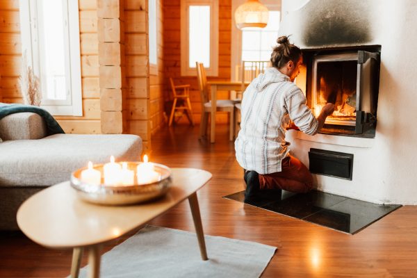 A man lights the fireplace at the Käpälämäki cottage.